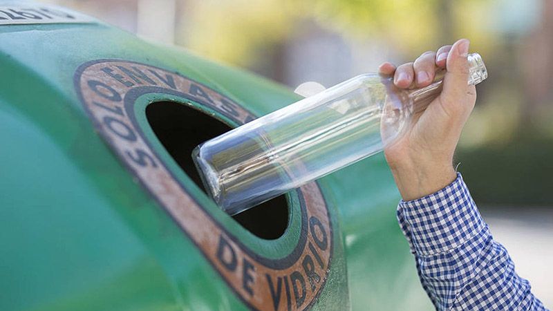 persona depositando una botella de vidrio en contenedor de Ecovidrio