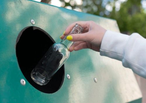 persona depositando envase de vidrio en contenerdor-verde-vidrio