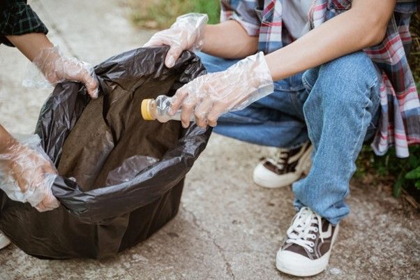 Persona recogiendo una botella de plástico del suelo