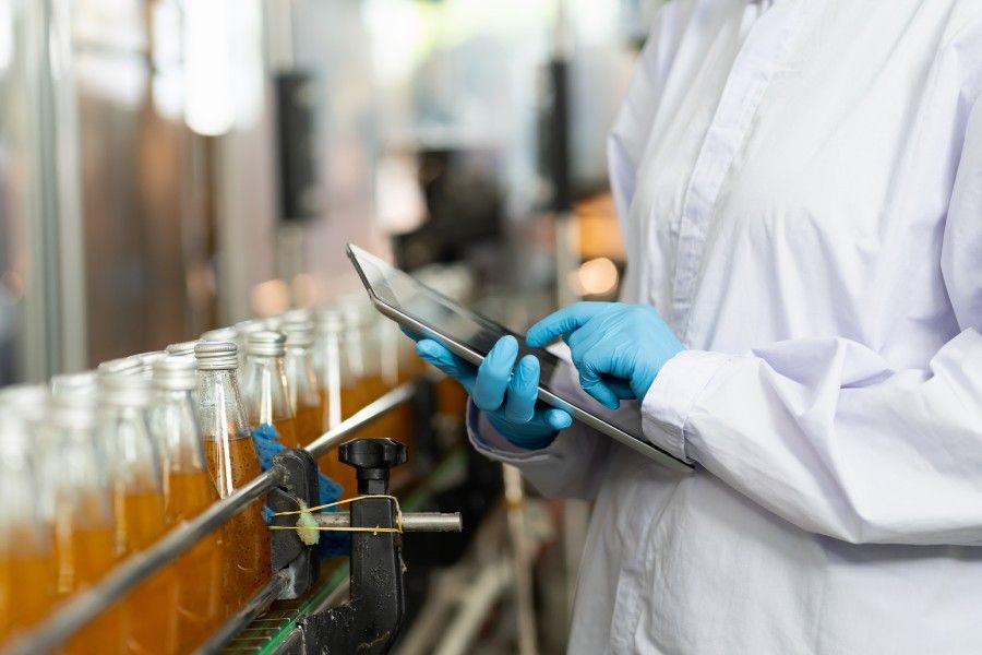 Persona analizando el diseño de botellas de vidrio con una tablet