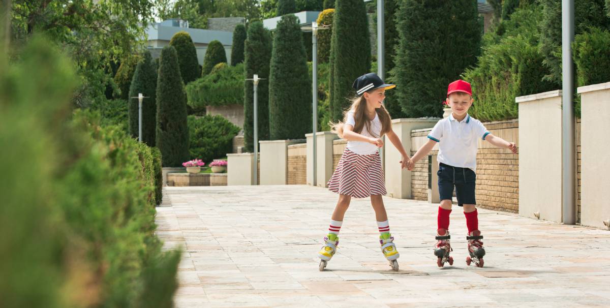 dos niños patinando por las calles de una ciudad