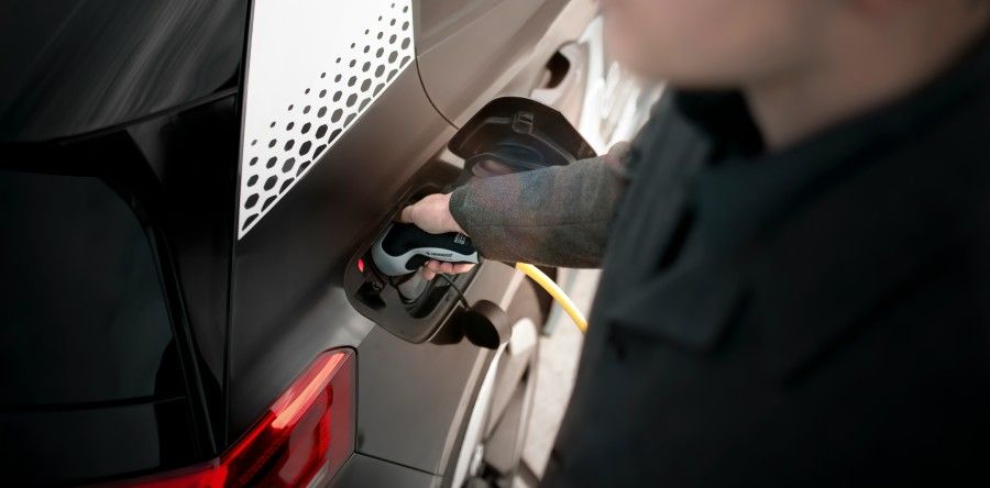 persona cargando batería del coche eléctrico